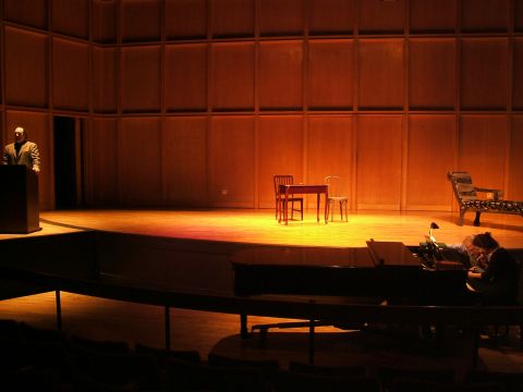 1996 Ford Probe - A stage is set with various furniture pieces and individuals, illuminated by warm lighting.