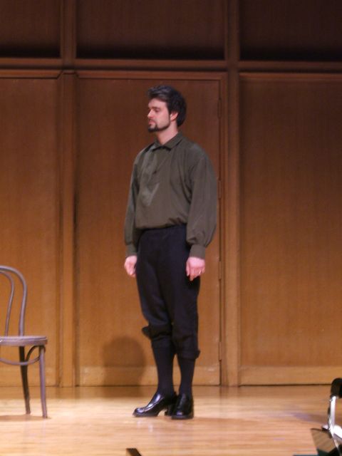 1996 Ford Probe - A man stands on a stage in front of a wooden backdrop, wearing a green shirt and dark pants.