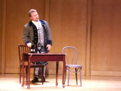 1996 Ford Probe - A man dressed in historical attire stands on a stage next to a table set with a bottle and a glass.