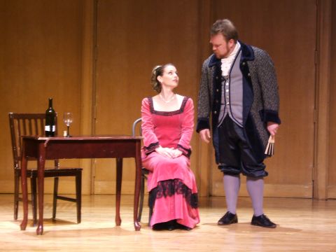 1996 Ford Probe - Two actors in elaborate period costumes are on a stage, with a table and chairs set to the side.