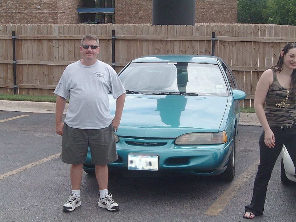 Teal sedan parked in a lot, front view