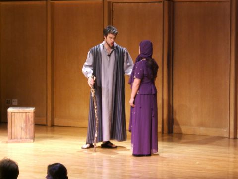 1996 Ford Probe - Two actors in period costumes perform on a wooden stage with a simple backdrop.