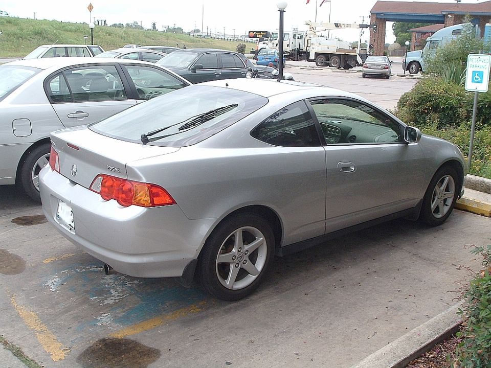 Silver coupe parked in a lot, rear quarter view. Honda badge visible on wheel