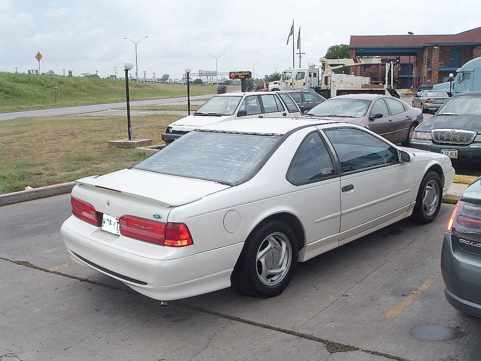 White Ford Thunderbird coupe rear three-quarter view parked in a lot with alloy wheels and spoiler