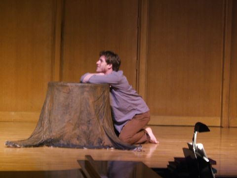 1996 Ford Probe - A man kneels on a wooden stage next to a prop tree stump, with a backdrop of wooden panels.