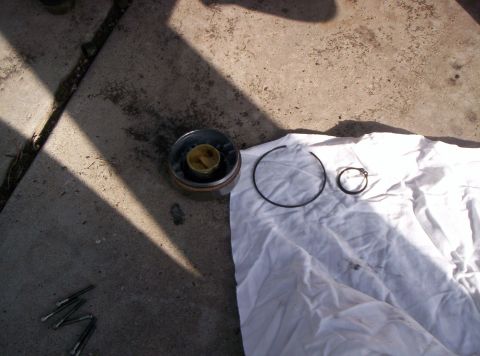 1986 Ford Bronco - A disassembled automotive part lies on a white cloth next to concrete.