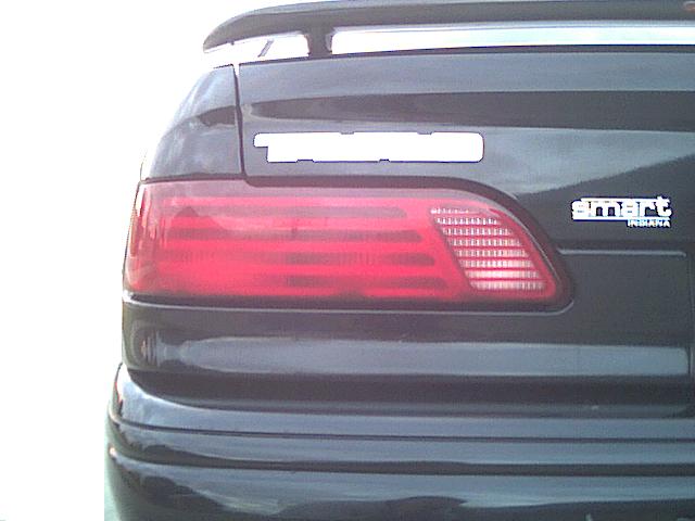 Rear tail light of a dark sedan with a 'smart INSANIA' decal