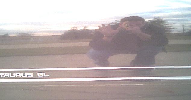 Chrome 'TAURUS GL' badge on car with person reflected taking photo