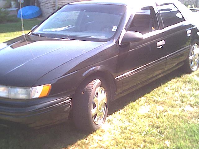 Black four-door sedan parked on grass, front-three-quarter driver's side view
