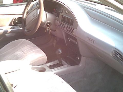 1993 Ford Taurus - The interior of a 1993 Ford Taurus shows gray cloth seats and a dashboard with a visible 'TAURUS' badge.
