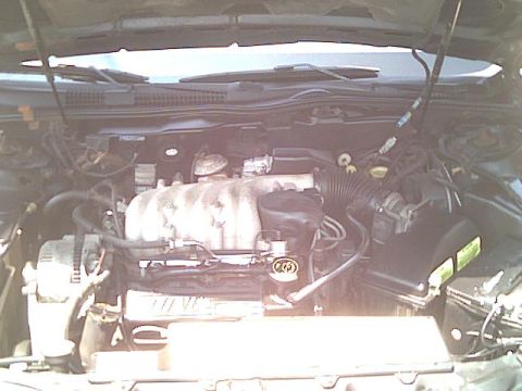 1993 Ford Taurus - The engine compartment of a vehicle is shown with various mechanical parts and wiring.