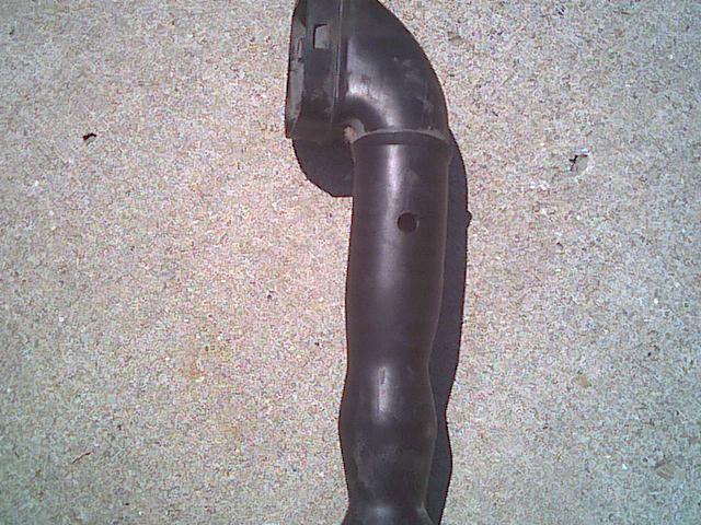 Curved black exhaust pipe with flange on concrete