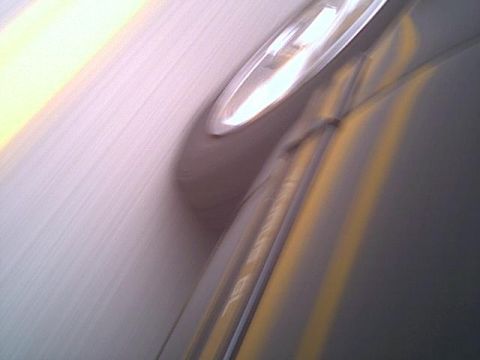 1993 Ford Taurus - A blurred side view of a dark car, showing a headlight and a yellow stripe.