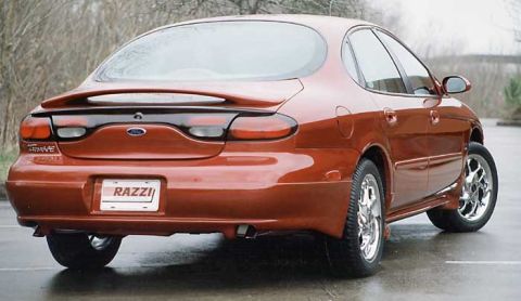 1993 Ford Taurus - Rear view of an orange sedan with a custom 'RAZZI' license plate and aftermarket wheels.