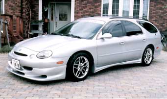 1993 Ford Taurus - This silver wagon features a custom body kit and aftermarket wheels, suggesting a model year around 1996 based on its styling.