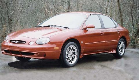 1993 Ford Taurus - This orange sedan features distinctive body lines and chrome wheels, captured in a front three-quarter perspective.
