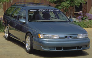 1993 Ford Taurus - A blue 1993 Ford Taurus wagon is parked outdoors with foliage in the background.