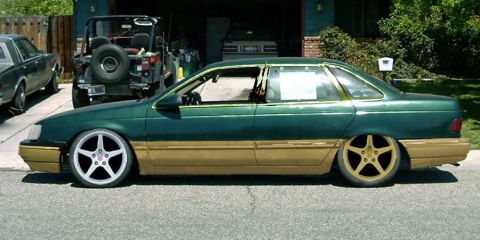 1993 Ford Taurus - A green sedan with gold lower body panels and aftermarket wheels is parked in a driveway.