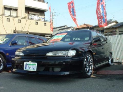 1993 Ford Taurus - Two cars parked outside a building with flags overhead.
