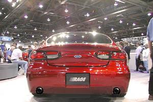 1993 Ford Taurus - Rear view of a red Ford sedan at an indoor event with people in the background.