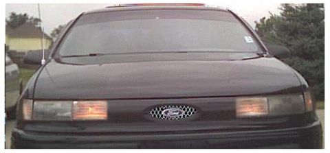 1993 Ford Taurus - Front view of a black Ford Taurus with a distinctive grille and tinted windows.
