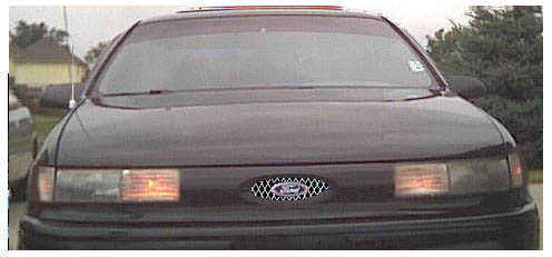 Front of dark Ford sedan with mesh grille insert at dusk