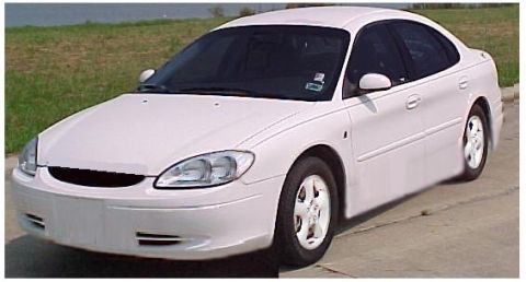 1993 Ford Taurus - This white sedan's body style suggests a model year around 2000, not 1993.