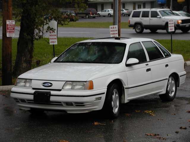 White first-generation Ford Taurus SHO sedan on wet pavement