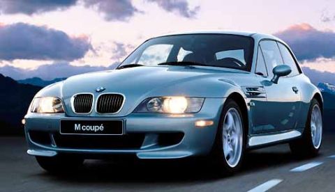 1993 Ford Taurus - A blue BMW M Coupé is shown from the front-three-quarter view against a dramatic sky.