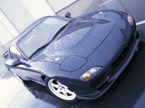 1993 Ford Taurus - A dark blue sports car is captured from a high angle, its surface covered in water droplets.