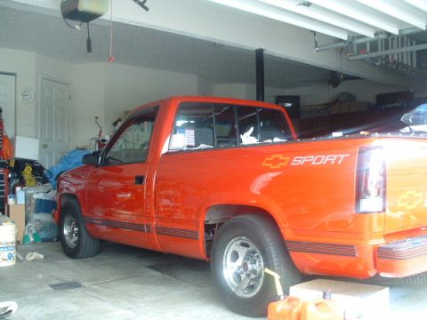 1993 Ford Taurus - An orange pickup truck is parked inside a garage, showing its side profile and a 'SPORT' decal on the rear quarter panel.