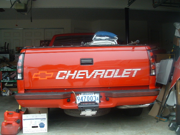 Rear tailgate of a red Chevrolet pickup with large Chevrolet decal, parked in a garage