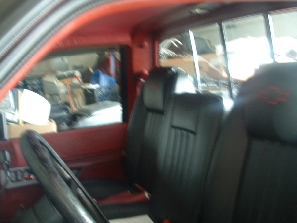 Red-trimmed Chevy pickup cab with black leather bowtie-embroidered bucket seats