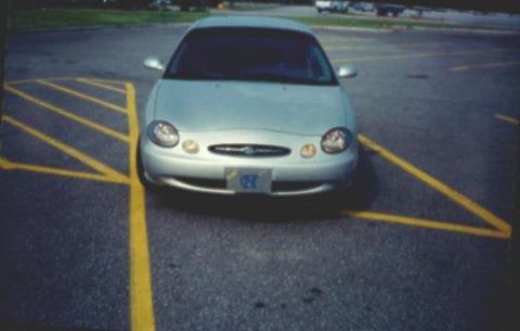 1998 Ford Taurus - A silver 1998 Ford Taurus is parked in a lot, facing the camera.