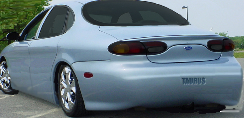 Light blue Ford Taurus sedan rear quarter view with custom wheels