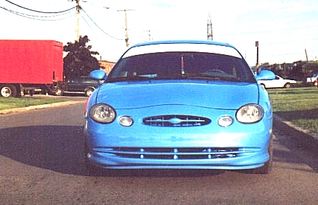 1998 Ford Taurus - Head-on view of a light blue oval-nose Ford Taurus sedan with a color-matched custom front fascia, body-colored grille bar and lower valanc…