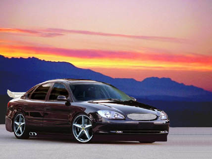 1998 Ford Taurus - Photoshopped rendering of a lowered dark cherry Ford Taurus sedan shown from the front three-quarter against a sunset mountain backdrop. Th…