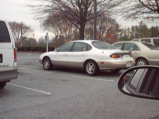 Silver Ford Taurus sedan, rear 3/4 in parking lot, with trunk spoiler