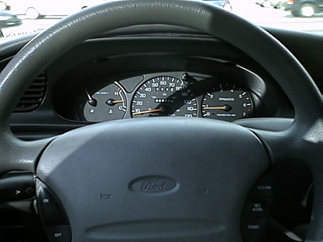 Ford gauge cluster behind steering wheel showing speedometer, tach and gauges