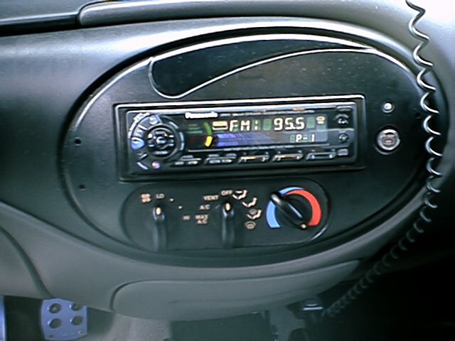 Aftermarket Panasonic car stereo head unit tuned to FM 95.5 in oval dash bezel