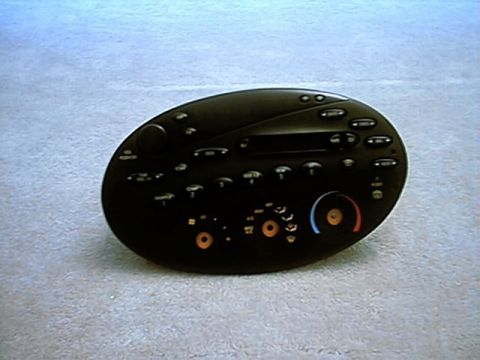 1998 Ford Taurus - Black oval heater and air-conditioning control panel with knobs removed, lying face-up on light gray carpet.