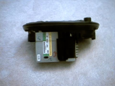 1998 Ford Taurus - A factory Ford audio module removed from a car and photographed on light carpet, showing the black plastic housing, a silver label with the…