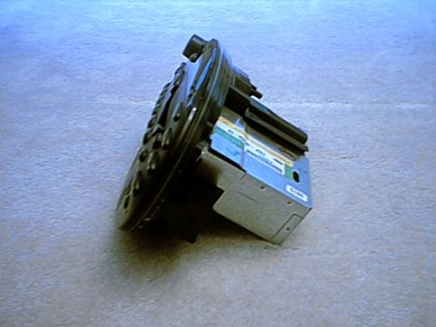 1998 Ford Taurus - A factory car stereo head unit removed from the dash and set face-down on grey carpet, showing the bare metal chassis, circuit board edge a…