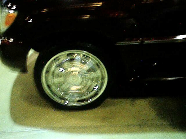 Close-up of a chrome spinner wheel blurred mid-spin on a dark car at night