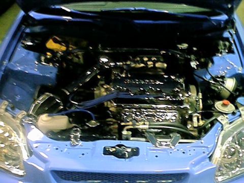 1998 Ford Taurus - The engine bay of a blue car is visible, black engine components and blue spark plug wires.