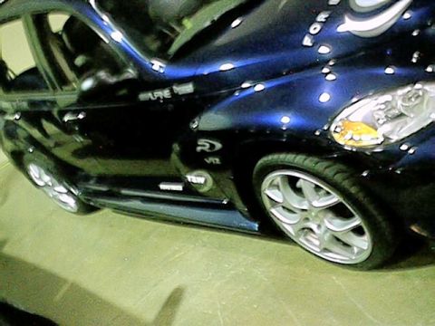 1998 Ford Taurus - Customized dark blue car with unique paint and alloy wheels is displayed at a car show.