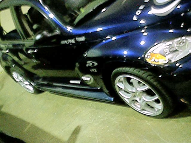 Dark blue car with custom paint and chrome wheels, seen from the front quarter angle