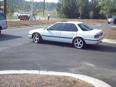 1998 Ford Taurus - A white sedan with custom wheels is seen from the side, appearing to be from the mid-1990s.
