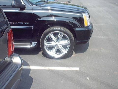 1998 Ford Taurus - A black SUV, identified as an Escalade EXT by its badging, is parked next to another vehicle.