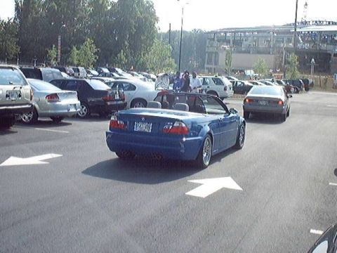 1998 Ford Taurus - A blue convertible is parked in a lot with other vehicles, with directional arrows painted on the asphalt.